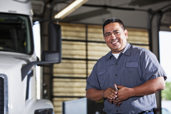 Hispanic mechanic in garage with truck